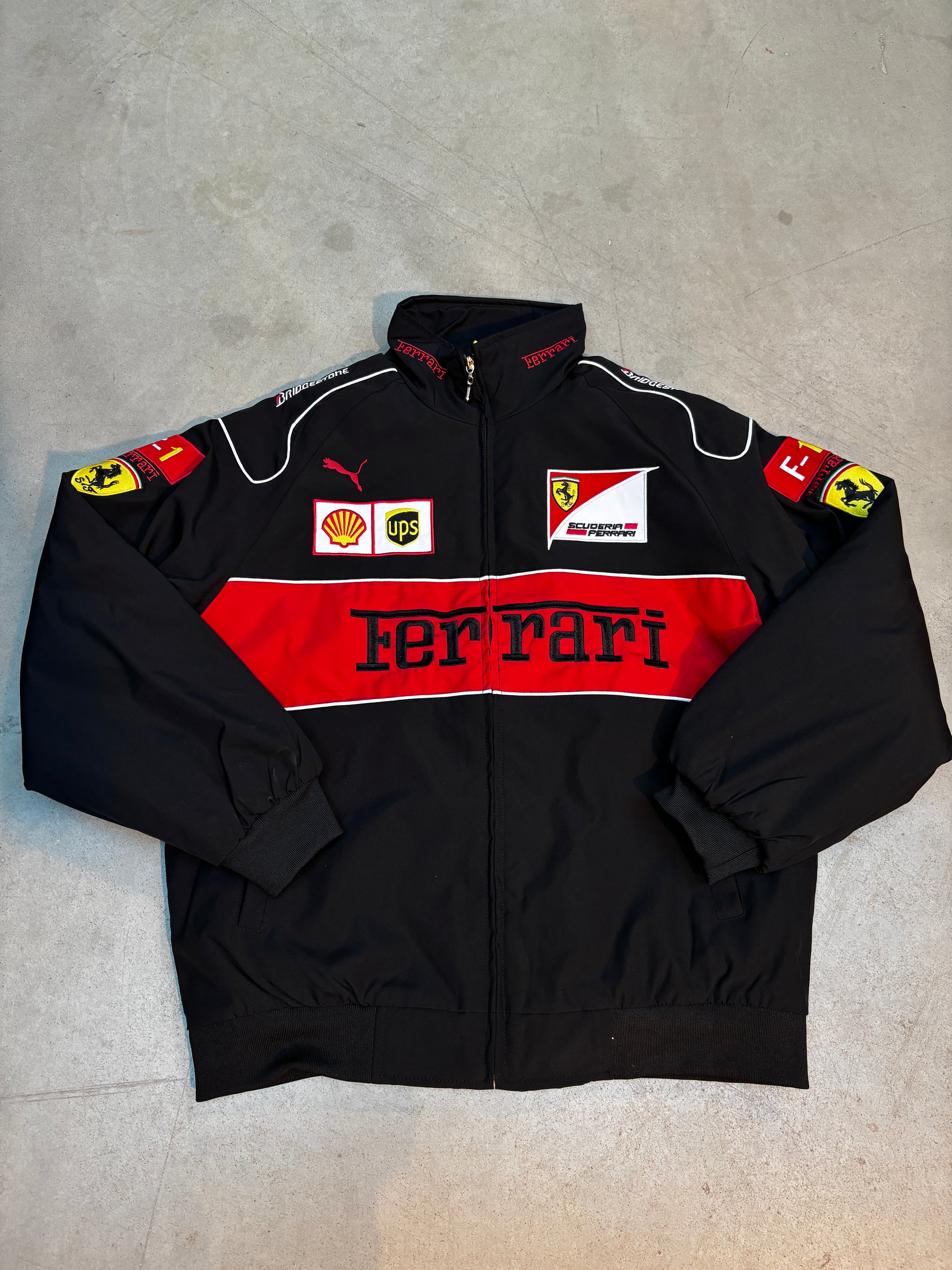 Black ferrari racing suit with red and white accents on a gray surface