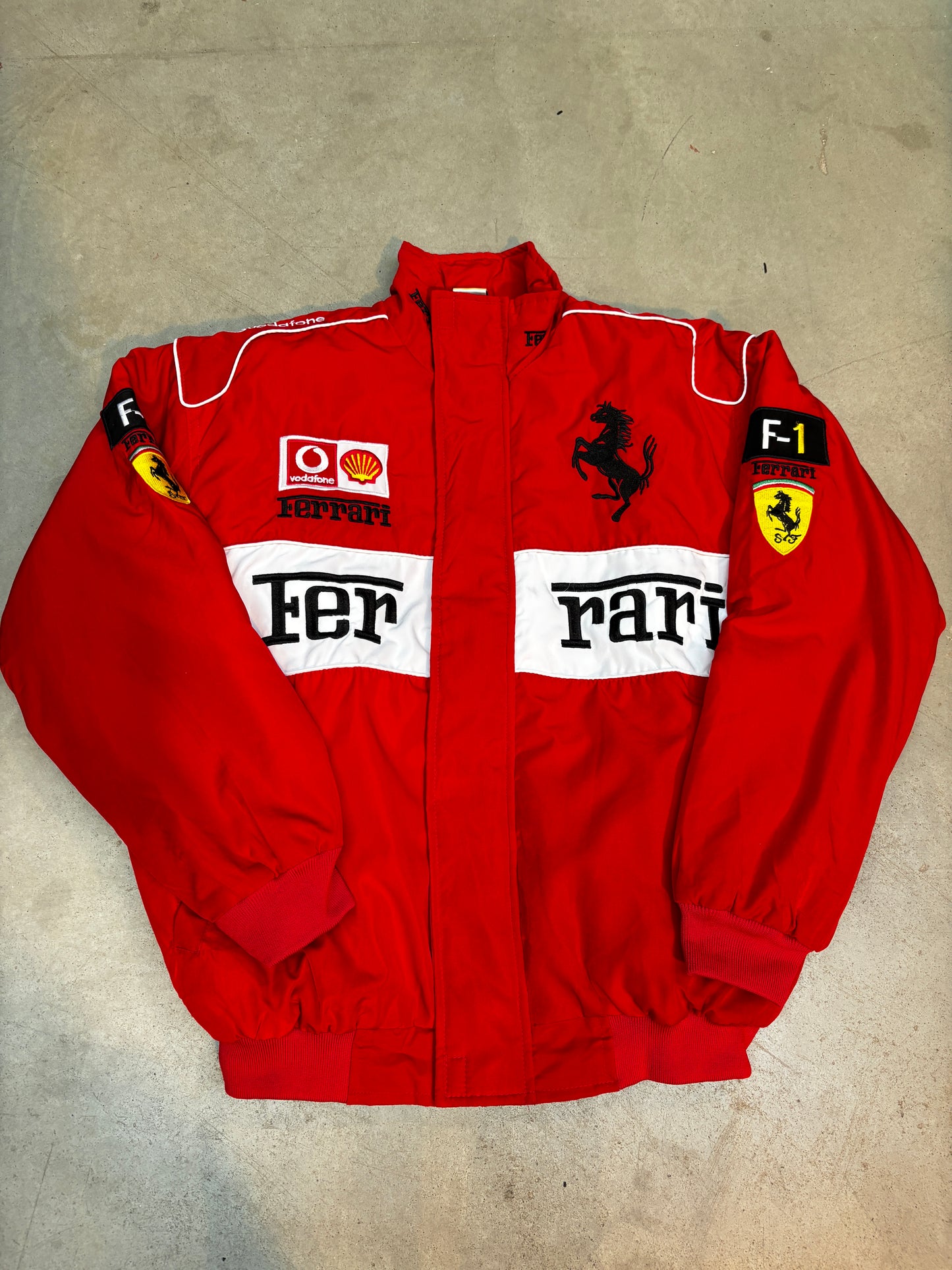 Folded red ferrari racing suit with visible branding on a beige surface