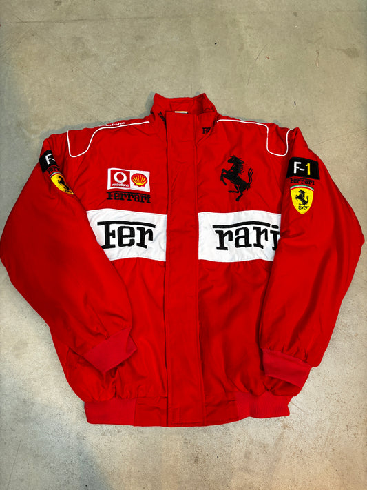 Folded red ferrari racing suit with visible branding on a beige surface